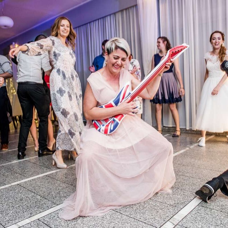 Panna młoda gra na dmuchanej gitarze podczas zabawy weselnej