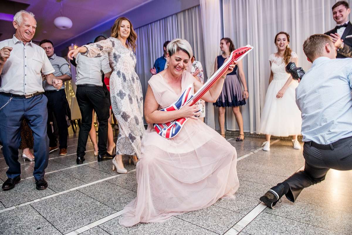 Panna młoda gra na dmuchanej gitarze podczas zabawy weselnej