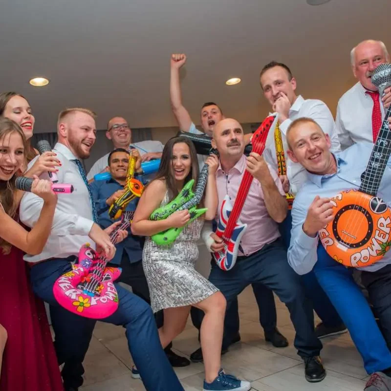 Goście weselni z kolorowymi dmuchanymi instrumentami podczas zabawy