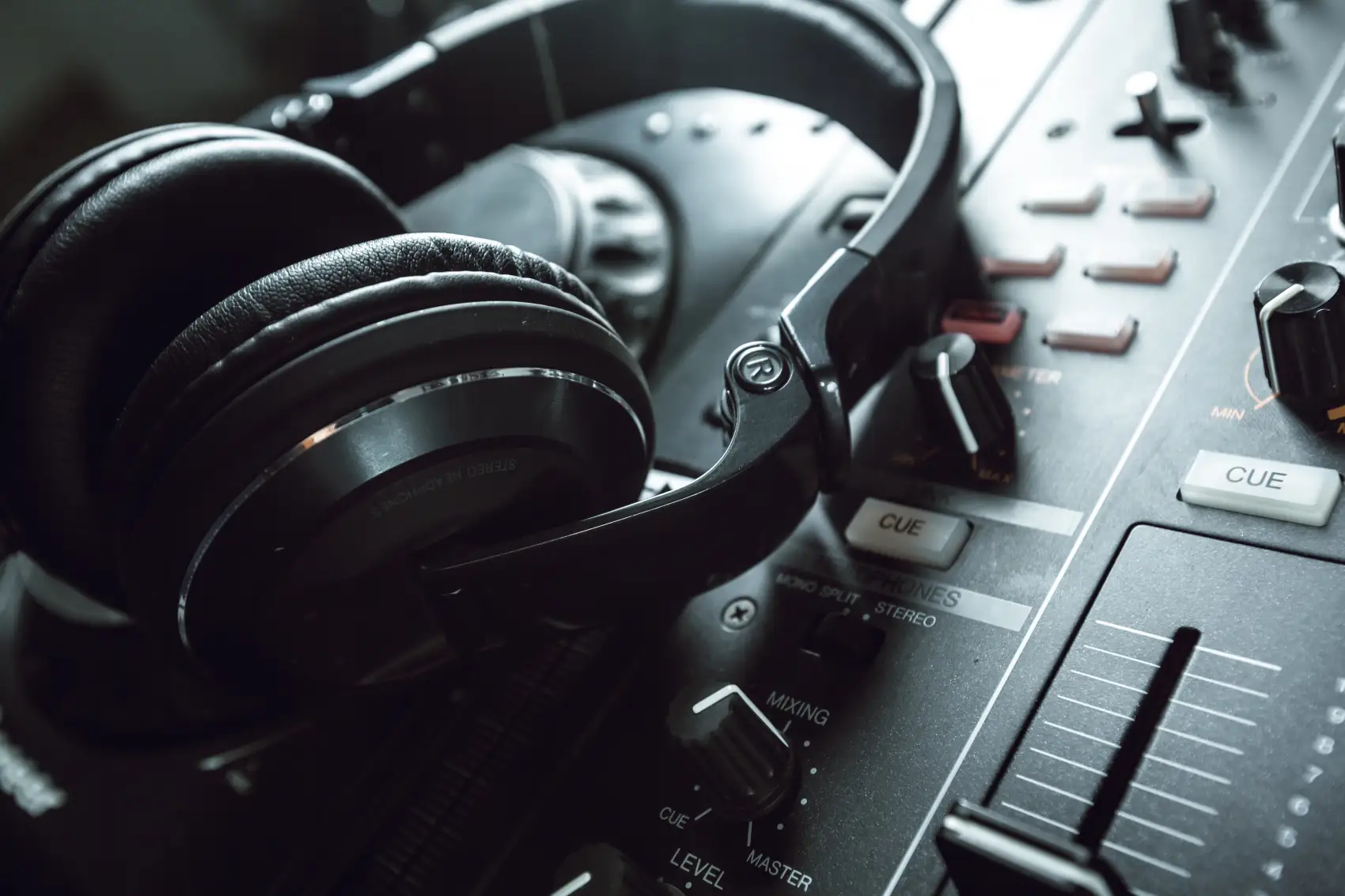Czarne profesjonalne słuchawki nauszne leżące na konsoli DJ-skiej z mikserem
